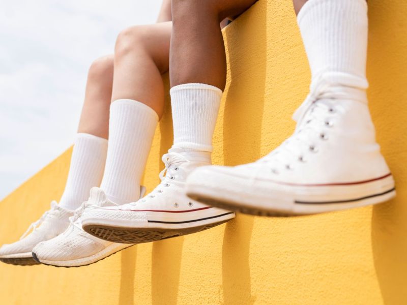 weisse sneaker vor einer gelben Wand
