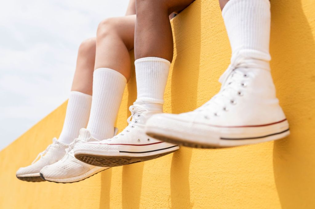 weisse sneaker vor einer gelben Wand