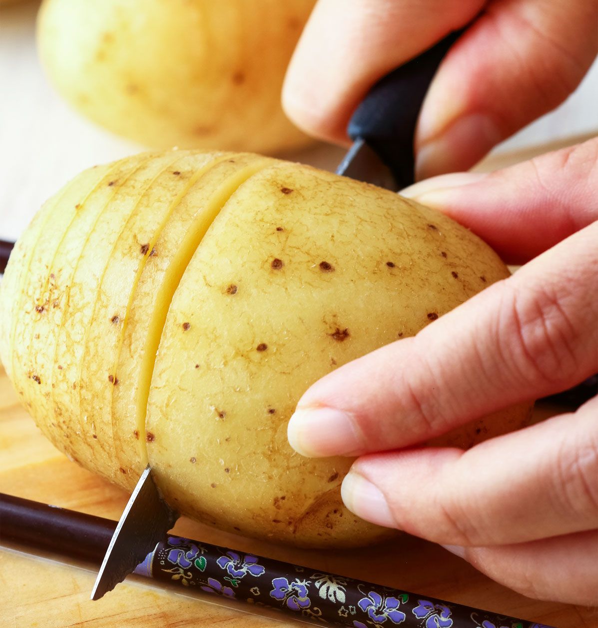 Mithilfe von Essstäbchen lassen sich Hasselback-Kartoffeln einfach schneiden