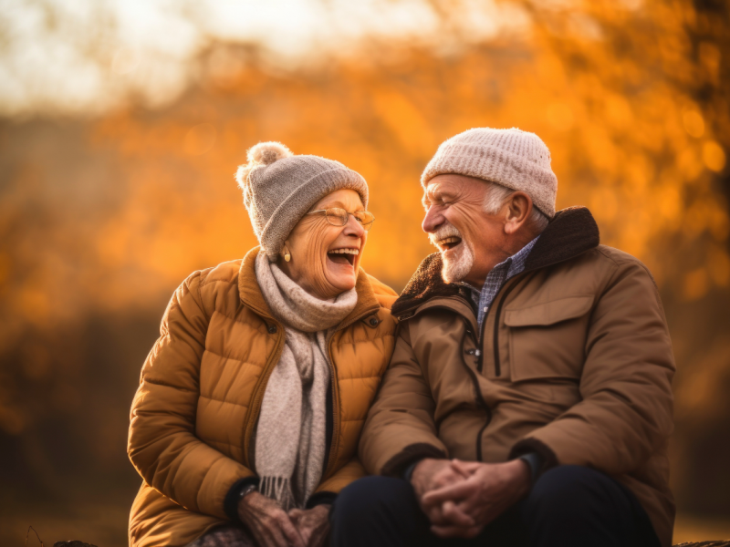 Oma und Opa auf einer Bank im Wald, die sich gegenseitig anlachen