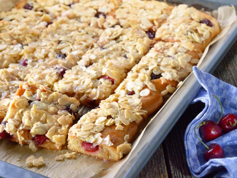 Butterkuchen mit Kirschen und Mandeln auf Backblech.