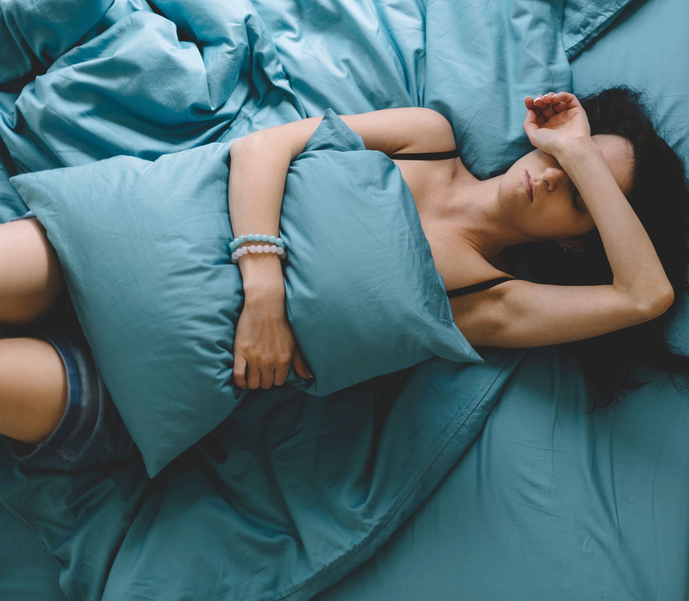 Weibliche Person liegt mit Kater-Beschwerden im Bett