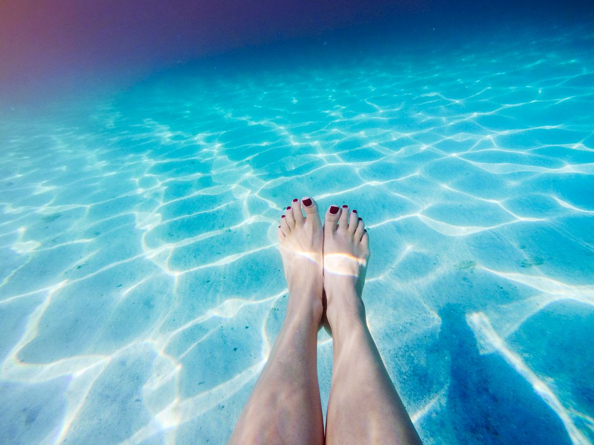 weibliche Person streckt die Beine unter Wasser