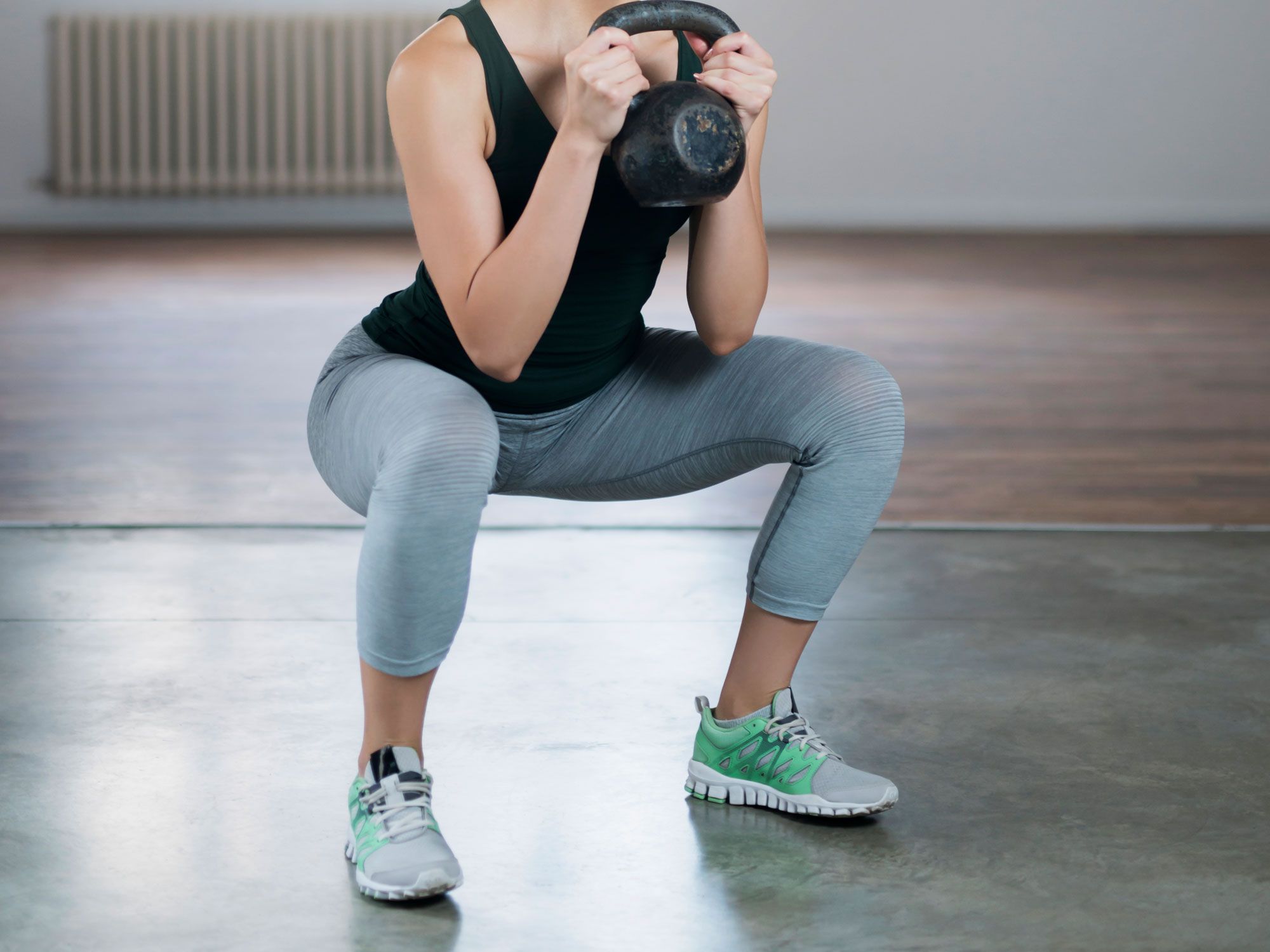 Frau führt Kniebeugen mit Kettlebell aus