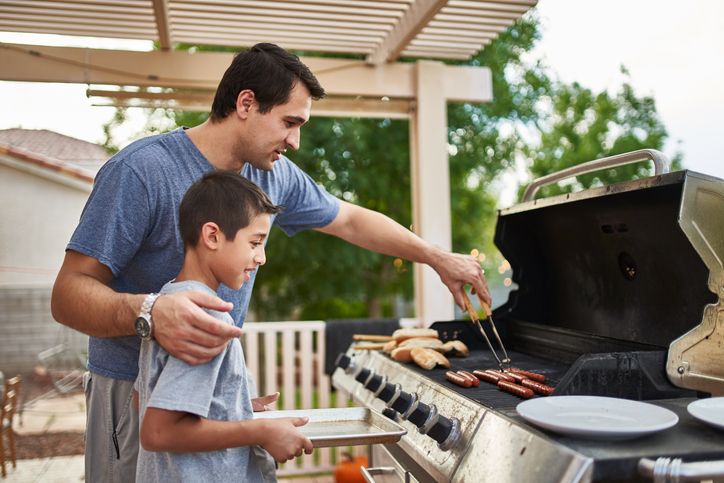 Vater und Sohn stehen am Grill