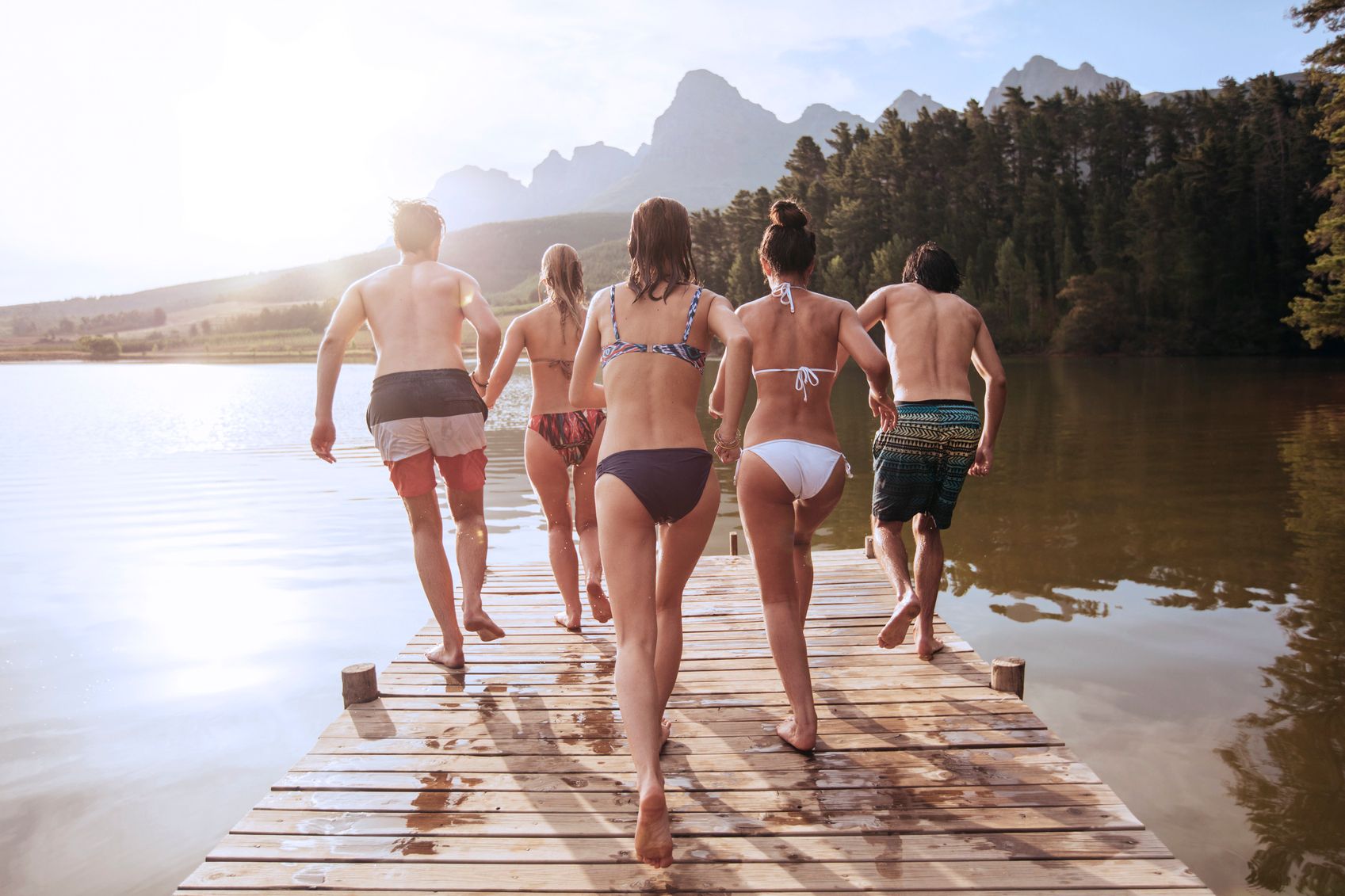 Nicht vergessen: Nach dem Baden die Badeklamotten zu wechseln. Gruppe junger sportlicher Leute geht schwimmen