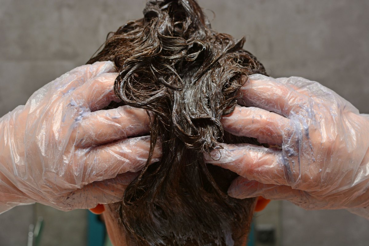 Frau, die sich gerade die Haare mit Coloration färbt.