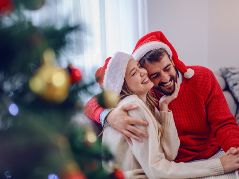 Paar an Weihnachten neben Weihnachtsbaum