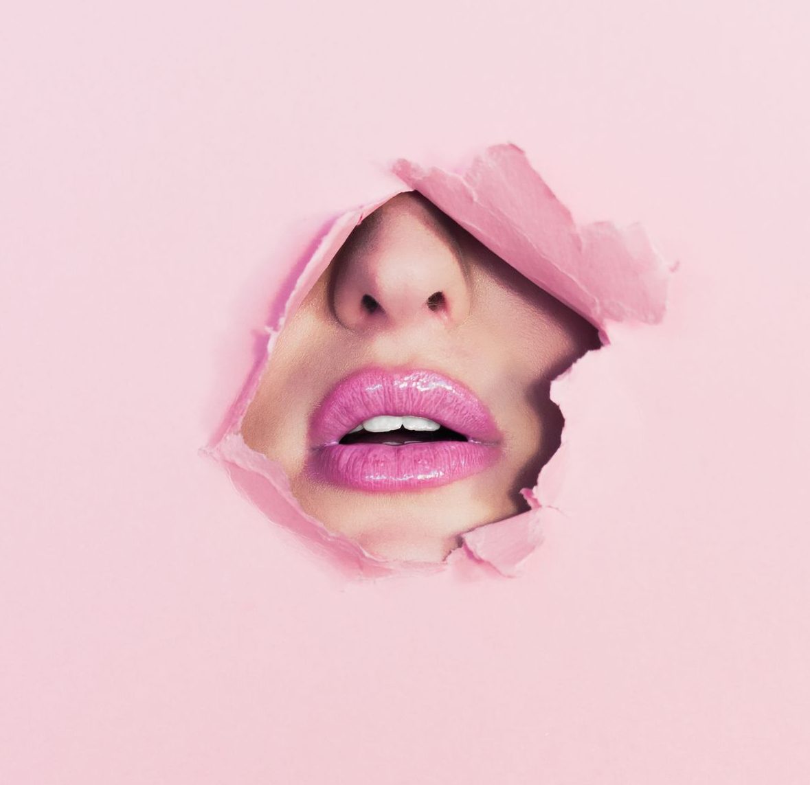 Teil eines weiblichen Gesichts ist durch Loch in rosa Wand zu sehen