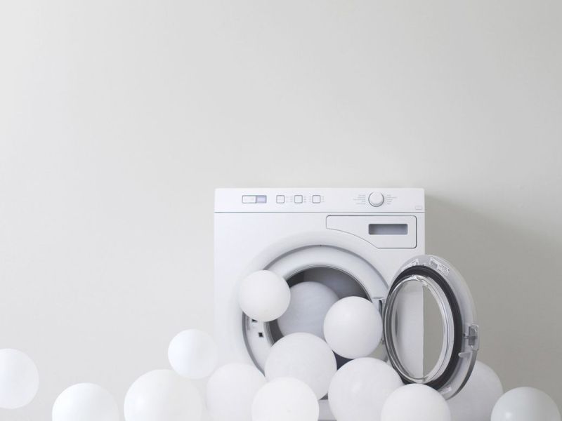 Waschmaschine mit weißen Ballons.