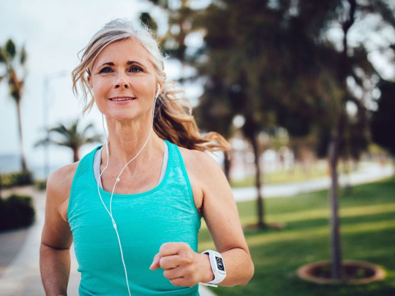 Frau mittleren Alters ist draußen joggen.