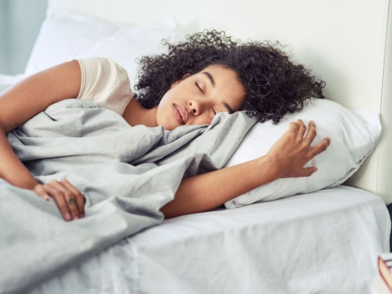 Frau liegt auf dem Bett auf einer Seite und schläft.