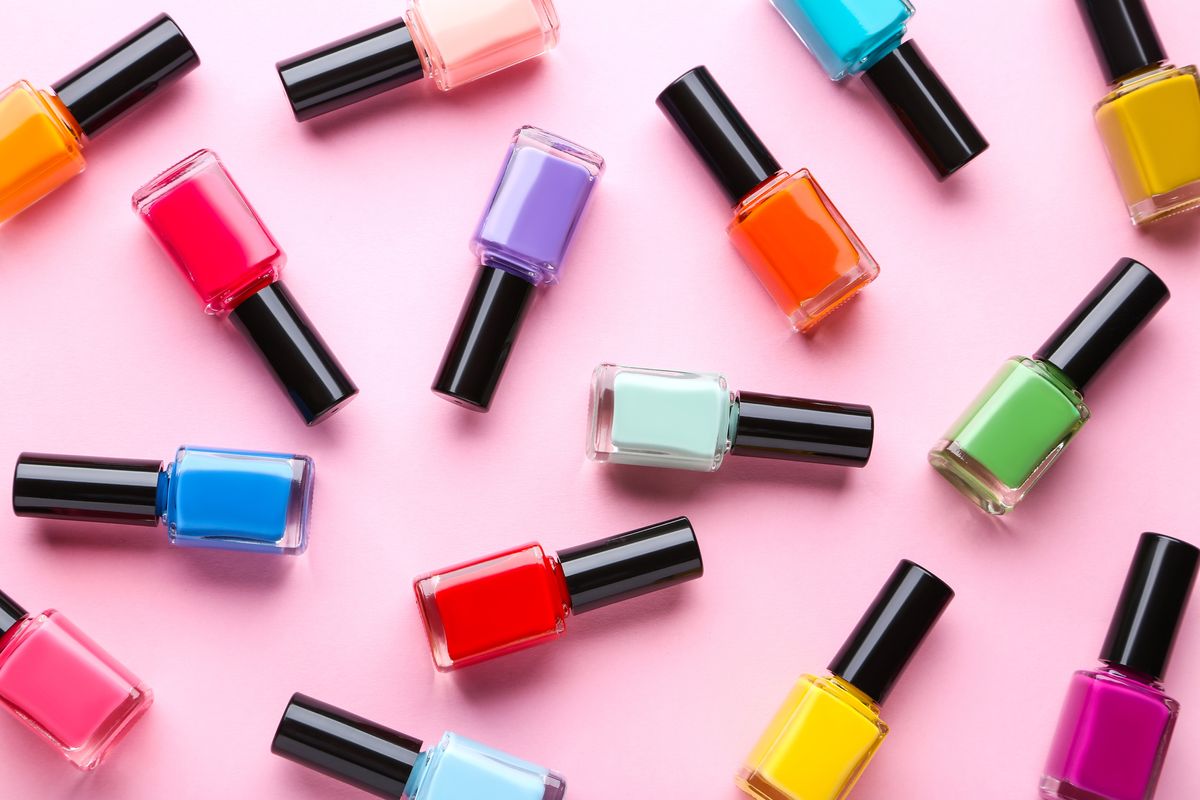 Bunte Nagellackflaschen vor einem rosa Hintergrund