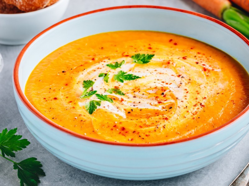 Karotten-Suppe in einer weißen Schüssel mit rotem Rand