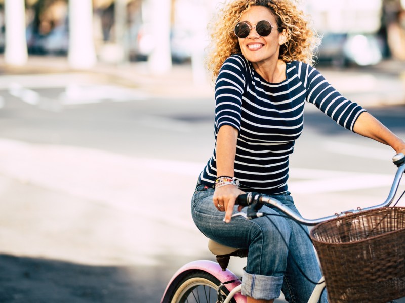 Frau mit Sonnenbrille auf dem Fahrrad in der Stadt