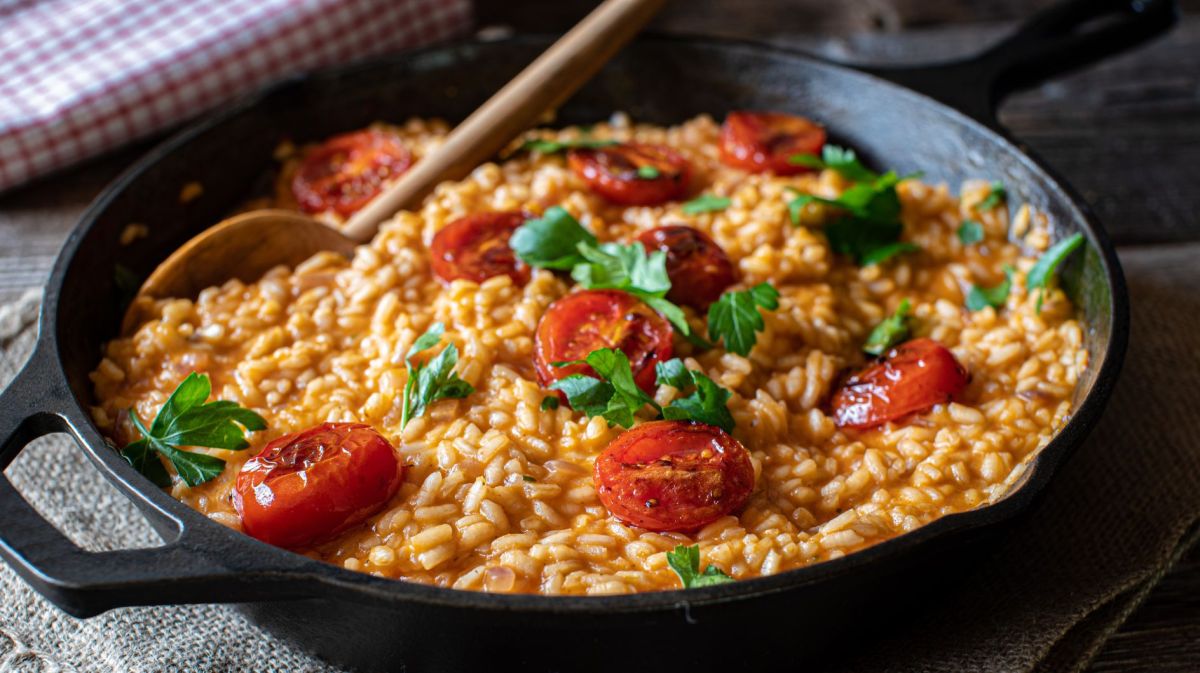 Risotto mit Tomaten in schwarzer Pfanne.