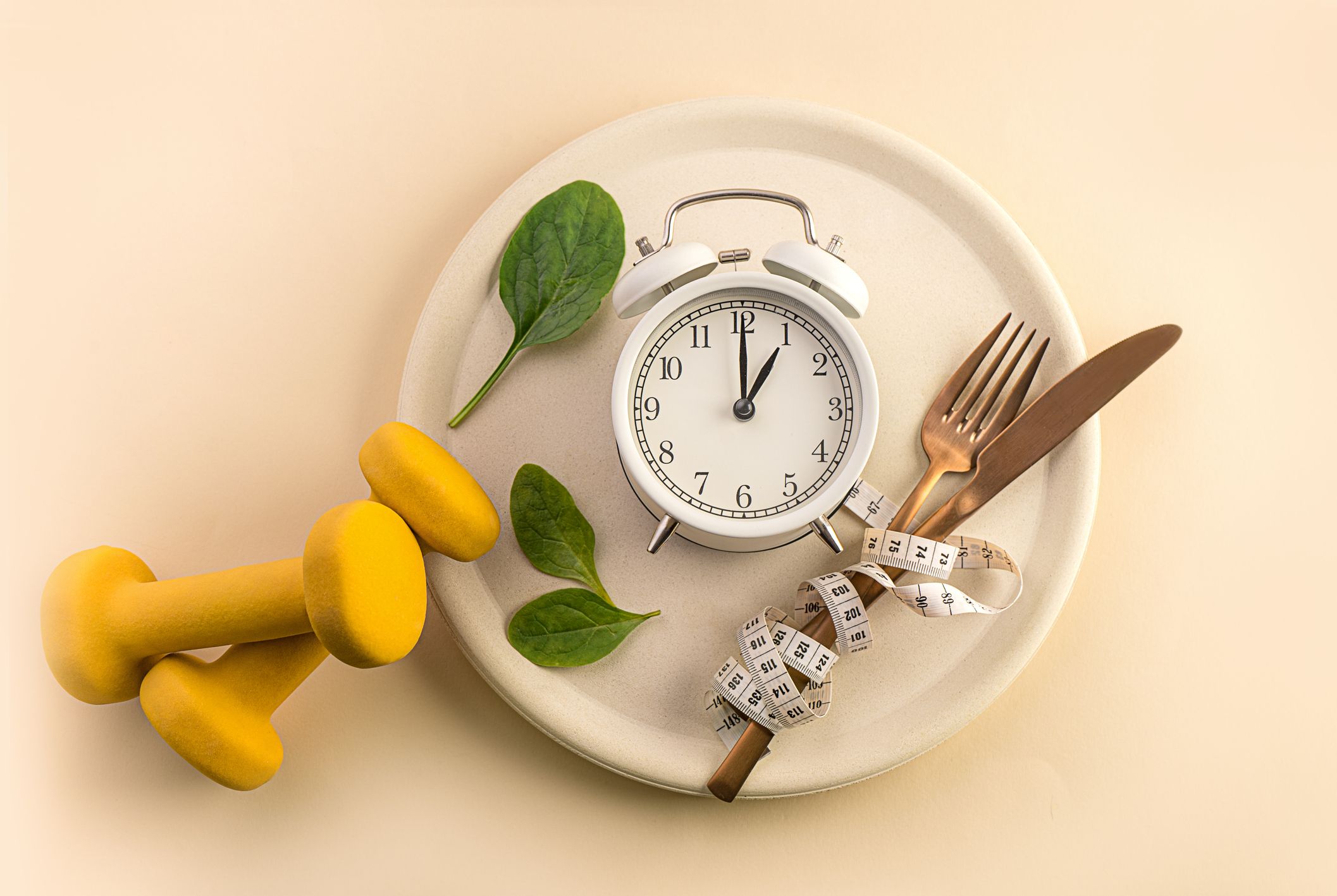 Speiseteller mit Besteck, Maßband, Uhr und Gewichten - Symbolbild für Intervallfasten