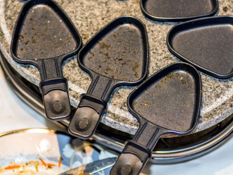 Schmutziges Raclette mit Pfännchen, bereit zum Raclette reinigen