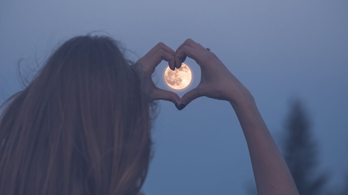 Person macht Liebeszeichen vor Vollmond