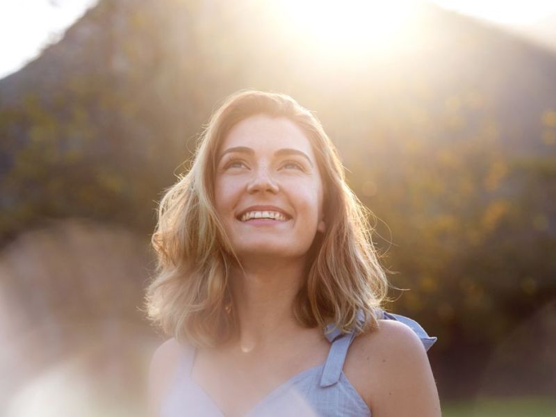 Frau schaut lächelnd in die Sonne 