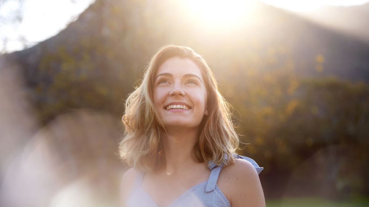 Frau schaut lächelnd in die Sonne 