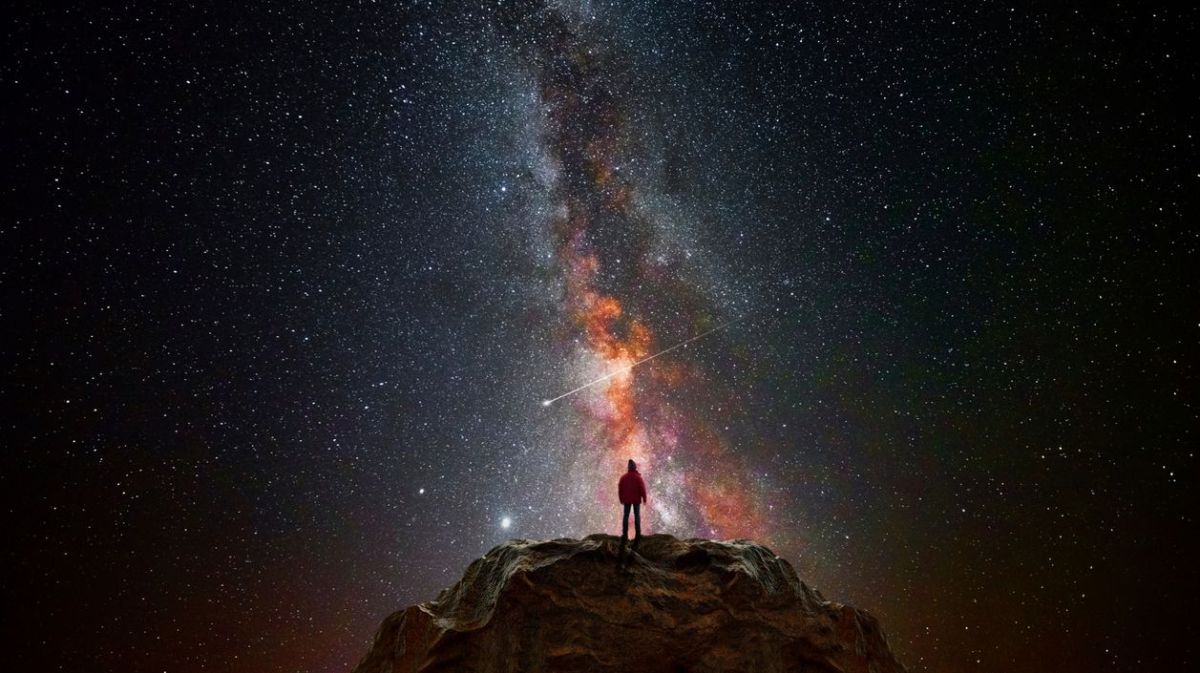 Frau schaut in den Sternenhimmel auf einem Berg 