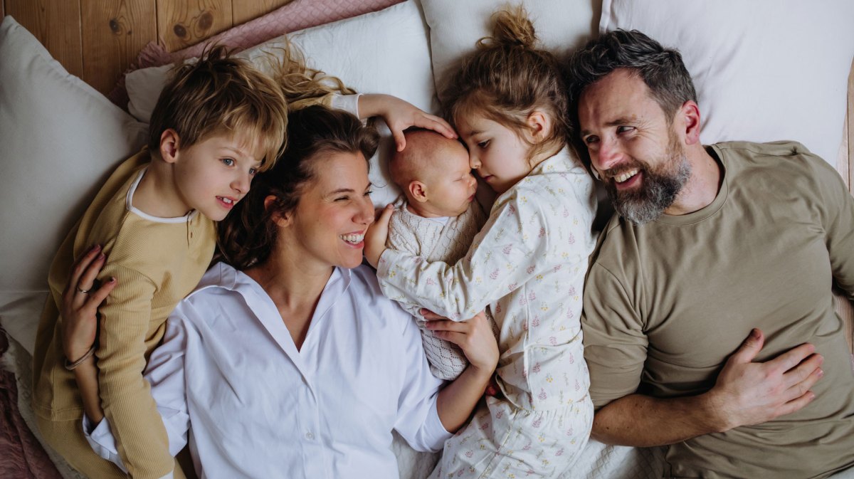 Fünfköpfige Familie liegt zusammen im Bett.