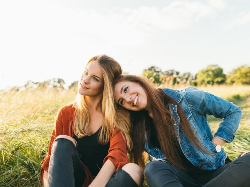 Zwei Freundinnen sitzen gemeinsam im Gras