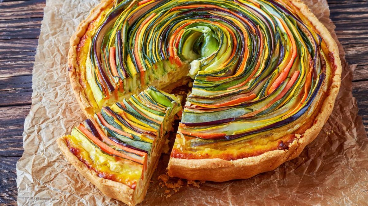 Bunte Spiral-Quiche mit verschiedenem Gemüse auf Backpapier.