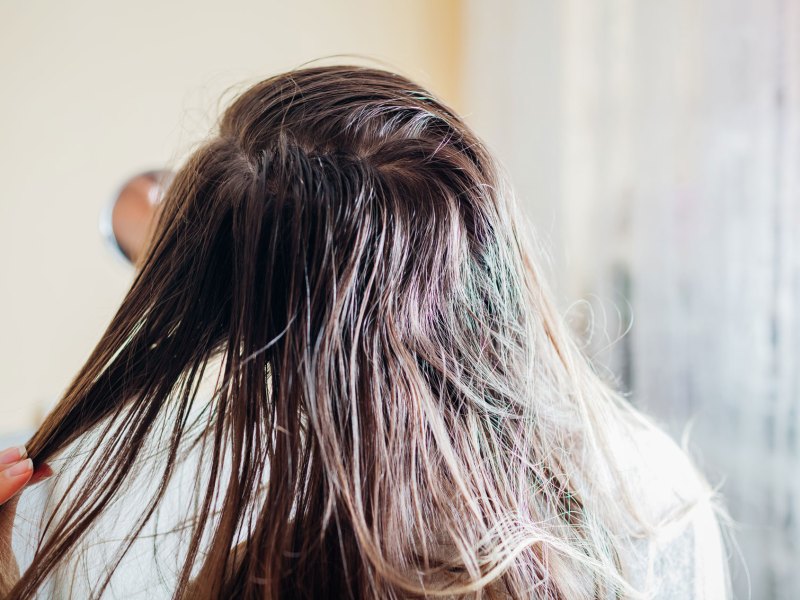 Frau mit fettigen Haaren, Ansätzen und Haarsträhnen.