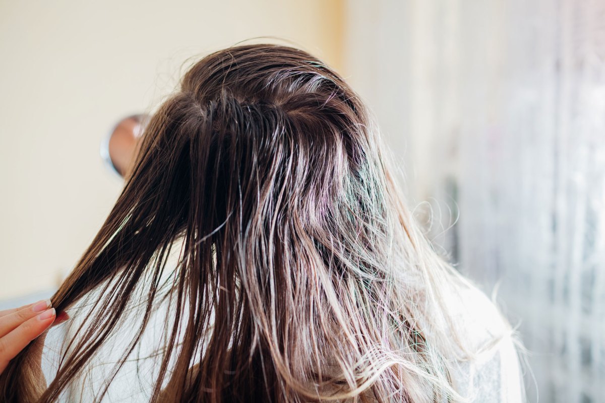 Frau mit fettigen Haaren, Ansätzen und Haarsträhnen.