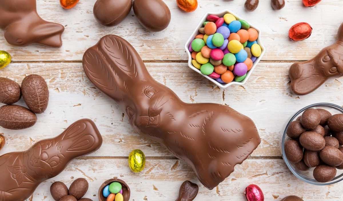 Schoko-Osterhasen und Ostereier auf einem rustikalen Untergrund.