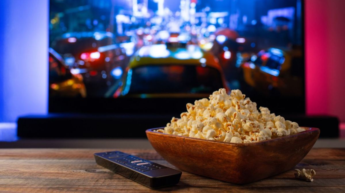 Fernseher mit Fernbedingung und Popcorn auf dem Tisch