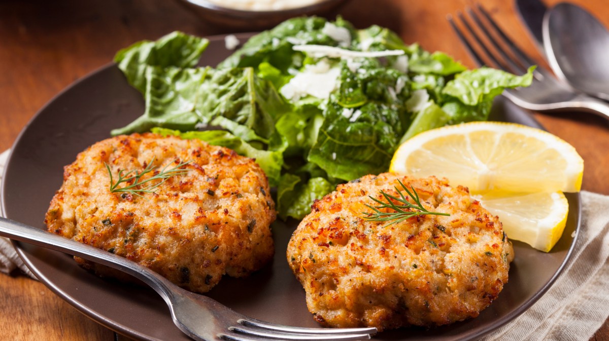 Crab Cakes mit Salat und einer Zitronenscheibe.