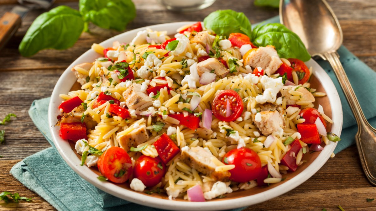 Orzo Salat mit Tomaten und Hähnchen in großer Schüssel.