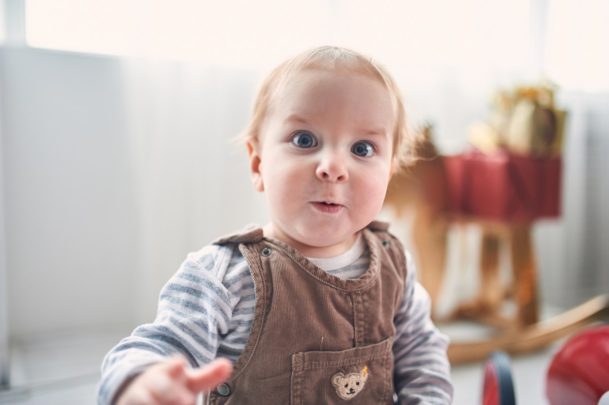 Porträt eines niedlichen 1 Jahr alten kleinen Jungen auf dem Boden sitzend.