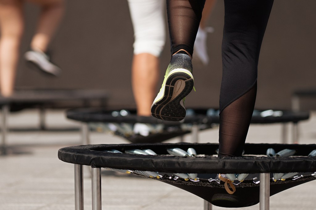 Man sieht die Beine einer Frau in Sportkleidung, die gerade auf einem Trampolin marschiert.