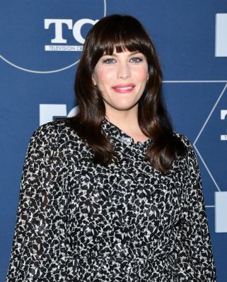 Der volle, gerade Pony von Liv Tyler verkürzt optisch die Stirn, während glänzende Wellen das Gesicht weich umrahmen. Der volle, gerade Pony von Liv Tyler verkürzt optisch die Stirn, während glänzende Wellen das Gesicht weich umrahmen.