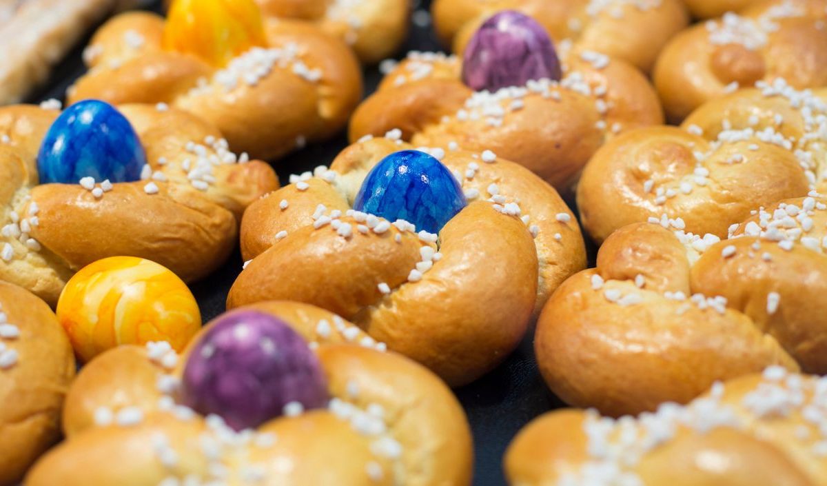 Mehrere Osternester aus Teig mit bunten Ostereiern in der Mitte.