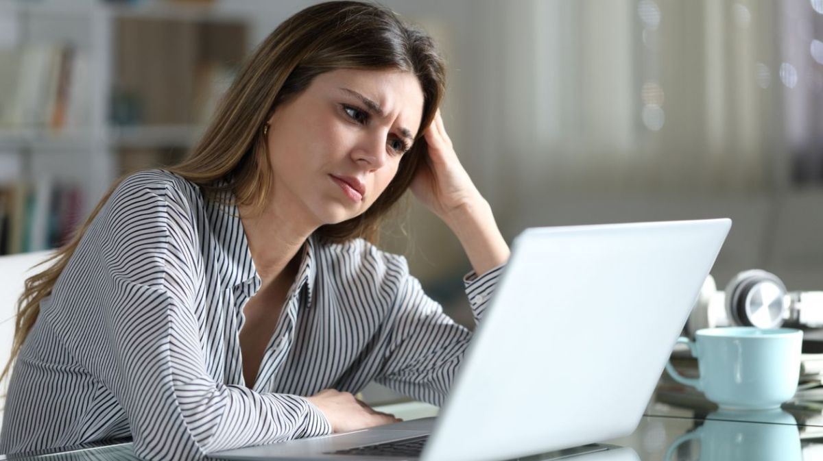 Frau sitzt gestresst vor dem Laptop. 