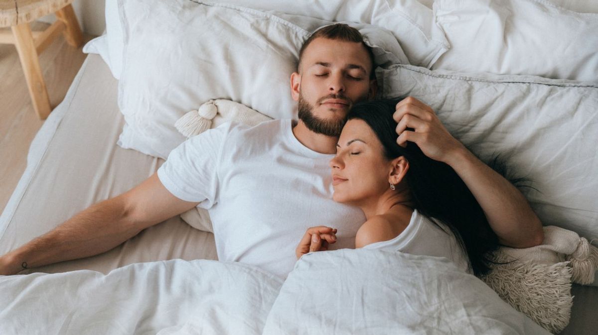 Pärchen kuschelt im Bett.