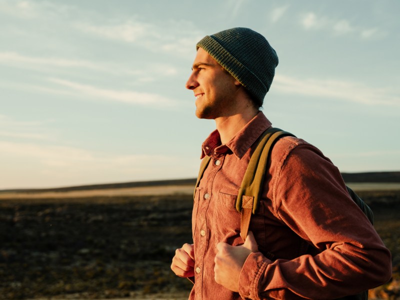 Mann mit Rucksack, der in die Sonne blickt