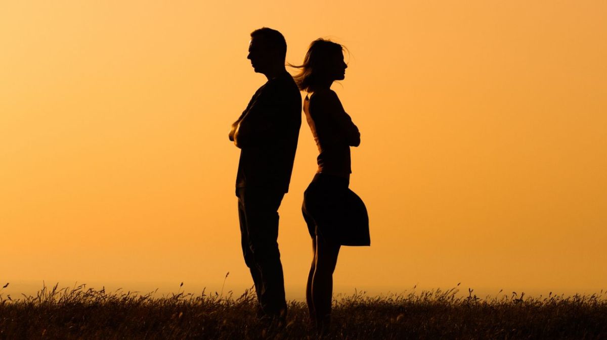 Die Silhouetten von zwei Personen vor orangem Hintergrund 