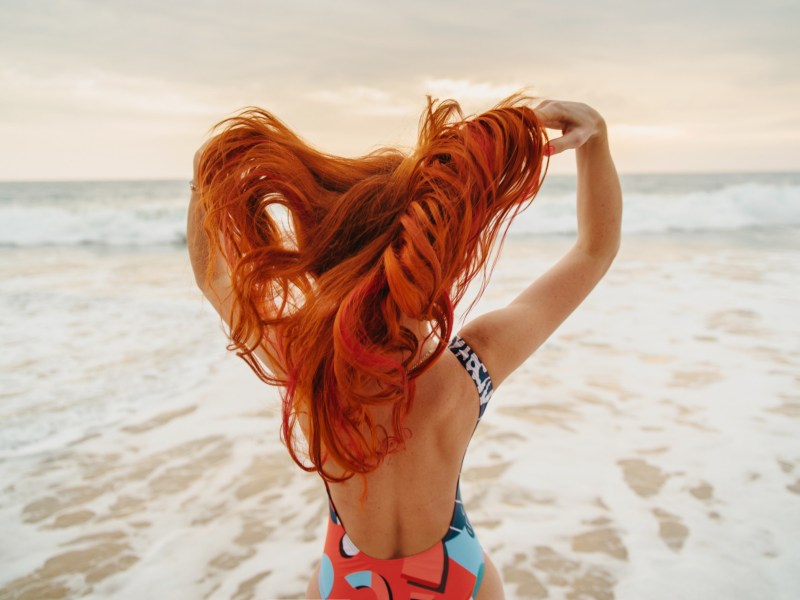 Frau mit roten Haare, die RIchtung Meer geht