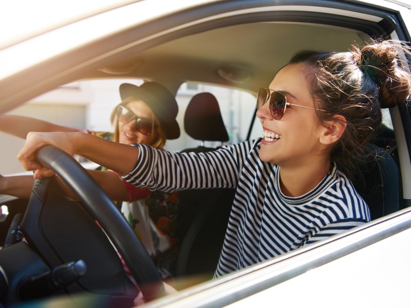 Frau sitzt im Auto und trägt Sonnenbrille.