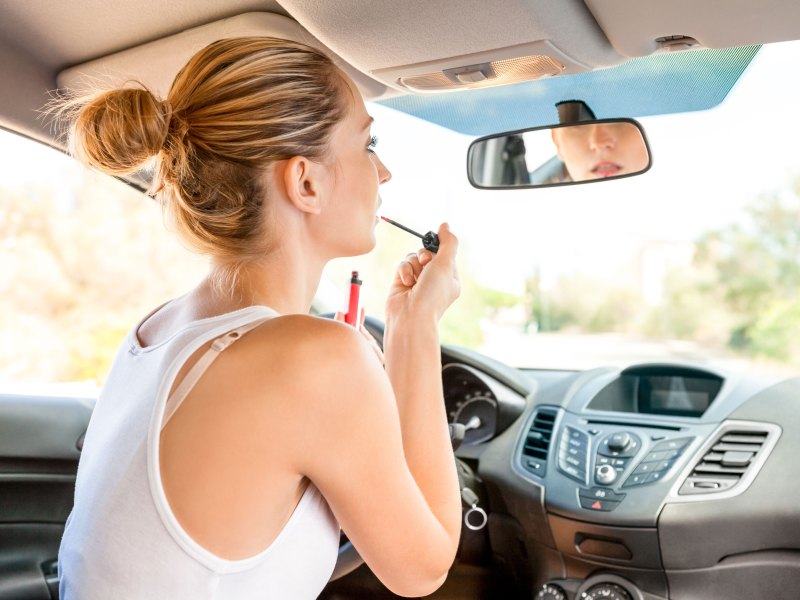 Frau schminkt sich im Auto