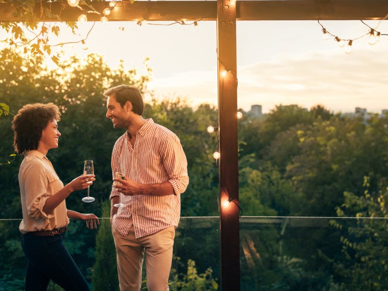 Mann und Frau auf Balkon mit Getränk in der Hand