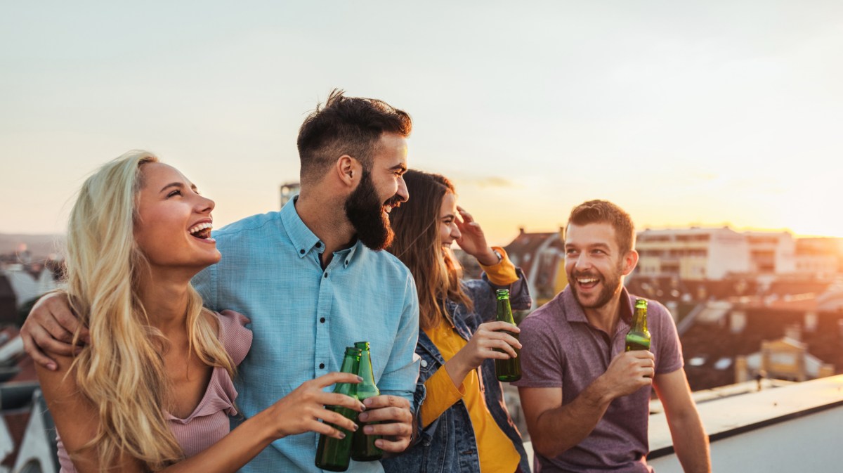 Freunde stehen gemeinsam auf Balkon im Sonnenuntergang