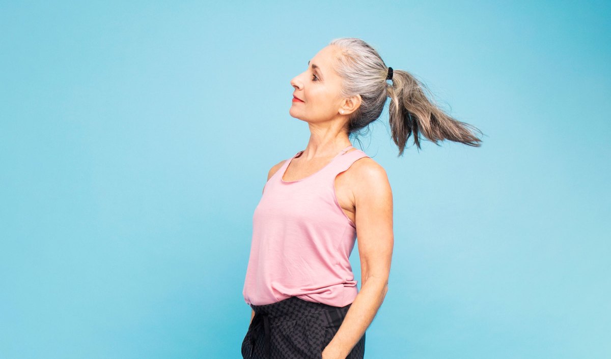 Frau mit 50 vor einer blauen Wand.