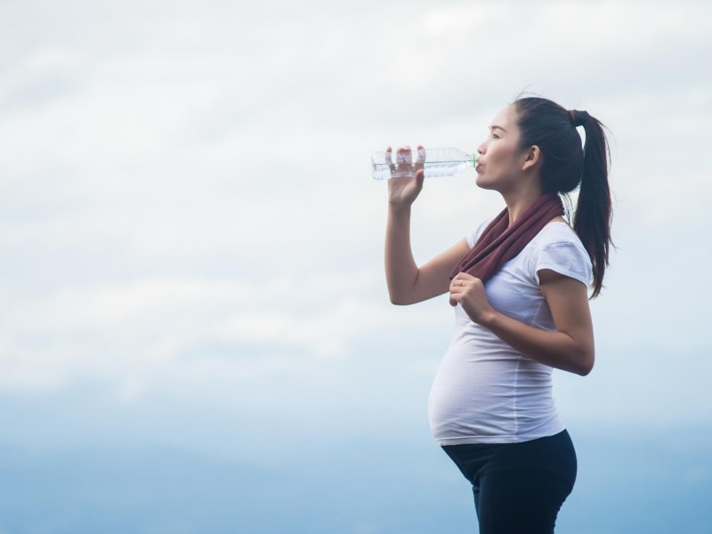 Schwangere Frau trink aus einer Wasserflasche